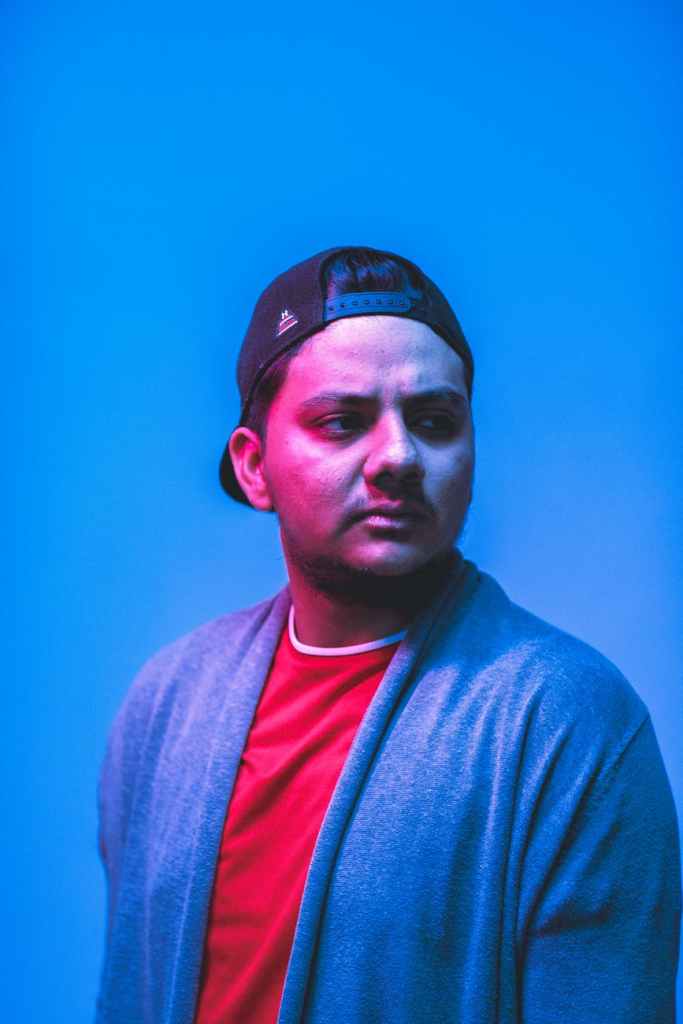 man wearing blue cardigan and black trucker cap