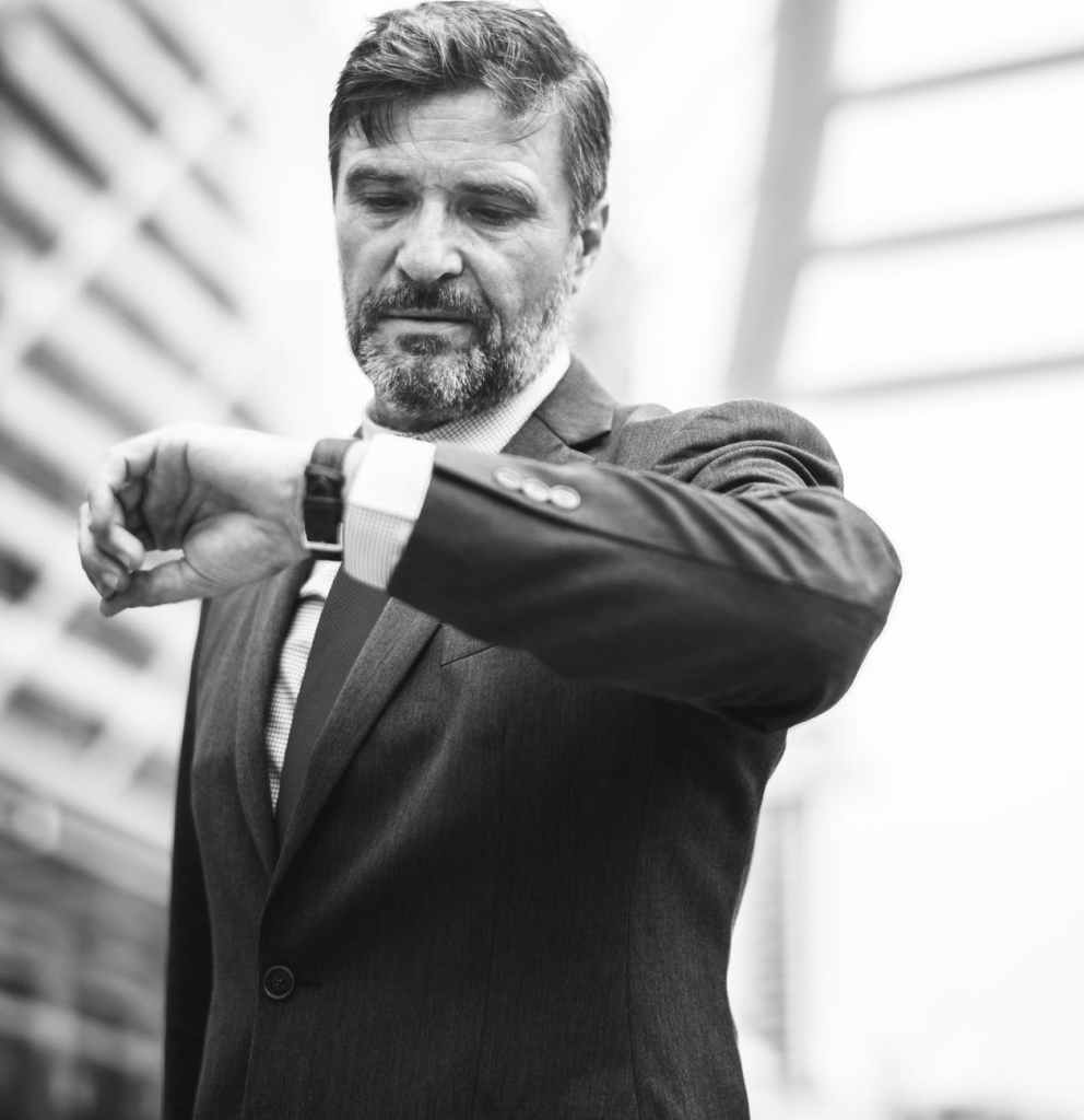 grayscale photo of man looking at his watch