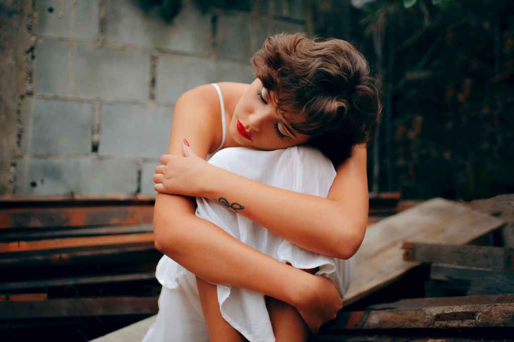 woman squatting near gray concrete wall